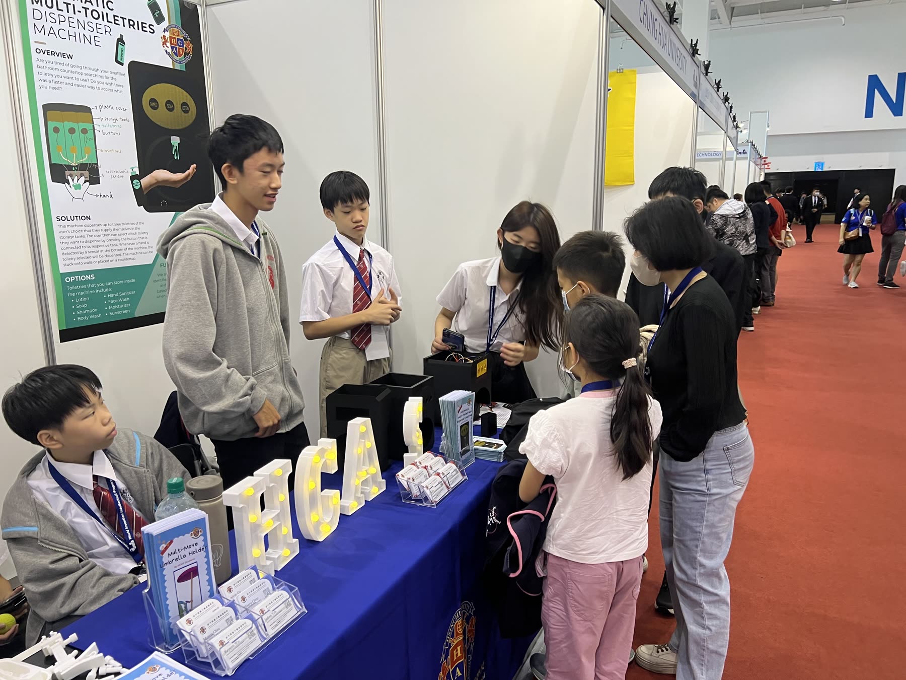 Students demonstrating the Automatic Multi-Toiletries Dispenser to visitors