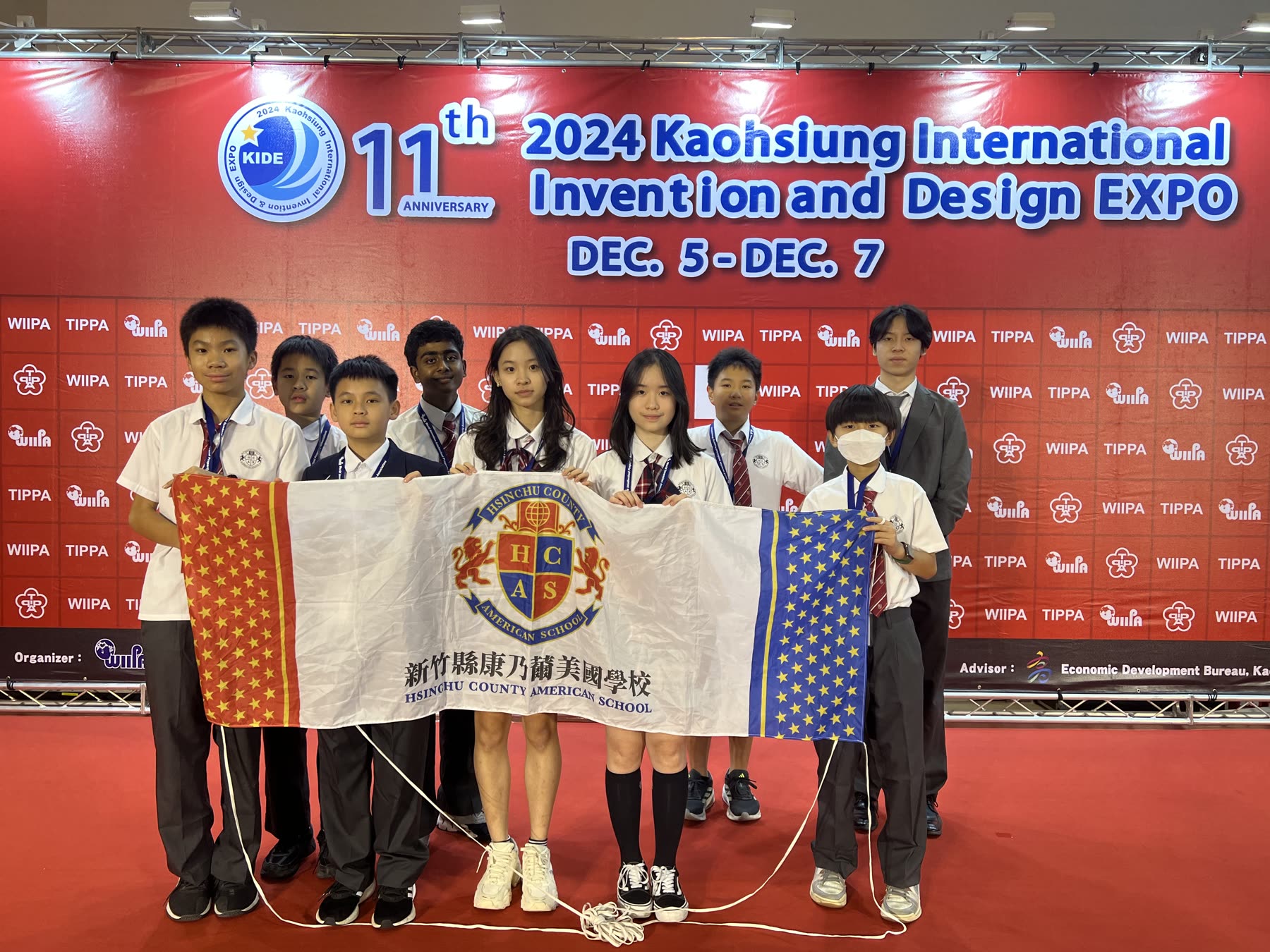 The HCAS Invention Lab team holding the school flag at the 2024 Kaohsiung International Invention and Design Expo